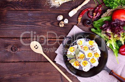 Black frying pan with fried quail eggs