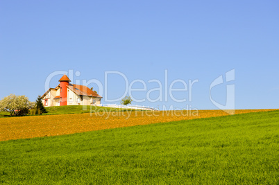 House with a turret over fields cultivated