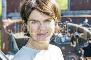 Woman stands in front of old scrap car