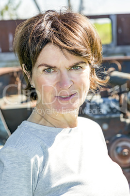 Woman stands in front of old scrap car
