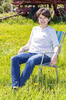 Woman sitting on garden chair in a flower meadow