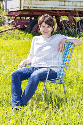 Woman sitting on garden chair in a flower meadow
