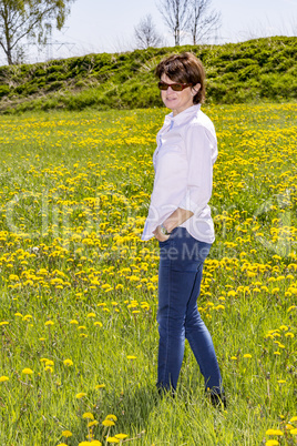 Middle-aged woman running over flower meadow