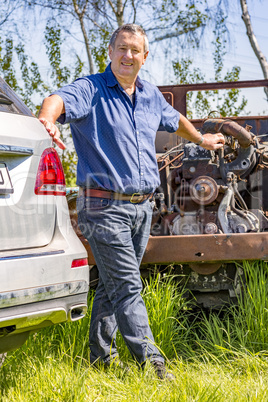 Man stands in front of old scrap car