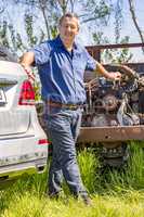 Man stands in front of old scrap car