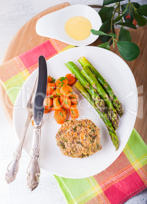 Meat rissole with glazed carrots, asparagus on the plate.