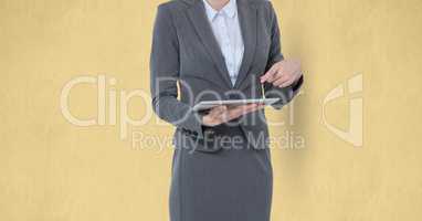 Midsection of businesswoman using digital tablet against yellow background