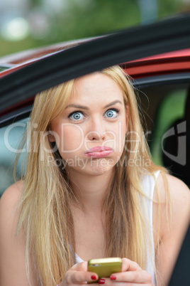 Beautiful blonde girl in a car using cell phone