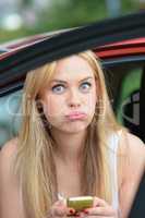 Beautiful blonde girl in a car using cell phone