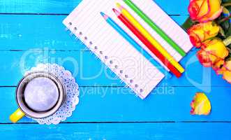 Empty paper notebook and colored pencils with a cup of black cof