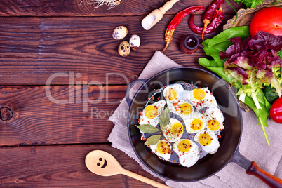 Fried quail eggs in a frying pan with spices