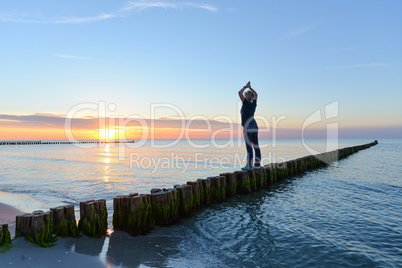 Frau macht Yoga im Sonnenuntergang am Meer