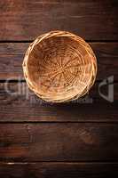 Empty wicker basket on a wooden background, top view