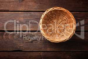 Empty wicker basket on a wooden background, top view