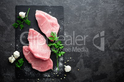 Raw meat, turkey steaks on black background, top view