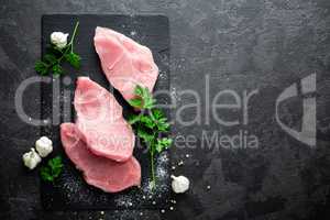Raw meat, turkey steaks on black background, top view