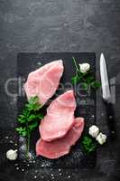 Raw meat, turkey steaks on black background, top view