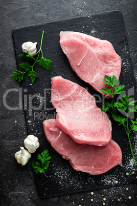 Raw meat, turkey steaks on black background, top view