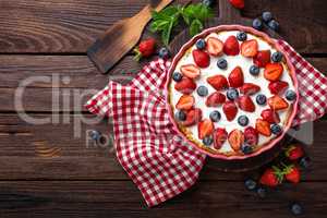 Delicious strawberry pie with fresh blueberry and whipped cream on wooden rustic table, cheesecake, top view