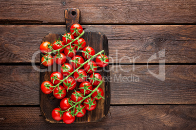 Fresh cherry tomatoes on twigs on wooden table, top view