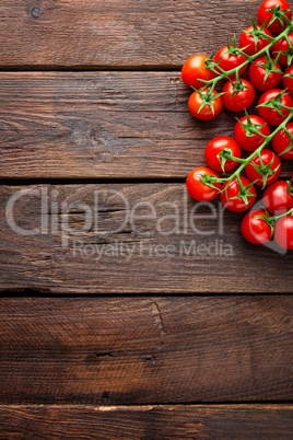 Fresh cherry tomatoes on twigs on wooden table, top view