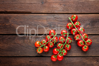 Fresh cherry tomatoes on twigs on wooden table, top view