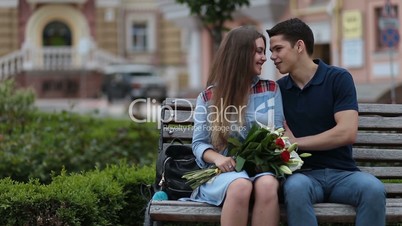 Attractive dating couple sitting on bench in park