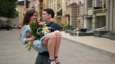 Handsome young man holding girlfriend in his arms