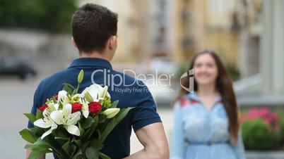 Young man hiding flowers for girl behind his back
