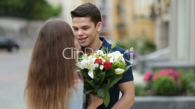 Handsome man surprising lovely woman with flowers