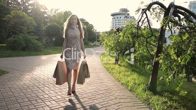 Elegant woman with shopping bags walking on street