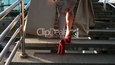 Elegant legs of woman with shopping bags on stairs