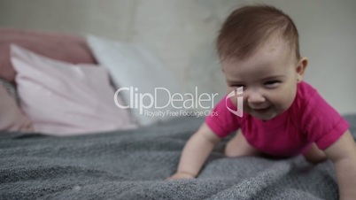 Happy baby girl crawling on bed