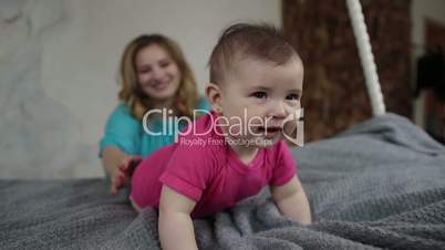 Adorable baby girl learning to crawl on bed