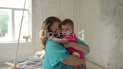 Caring young mom nursing infant child at home.