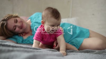 Lovely mother playing with newborn child in bed