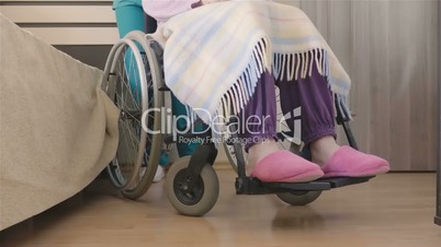 Young nurse caring of elder disabled woman in wheelchair
