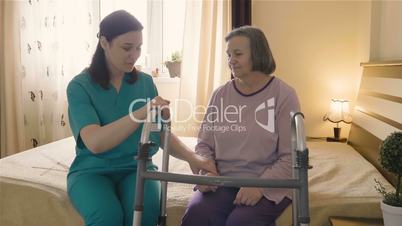 Caregiver helping senior woman getting up and walk with a walker