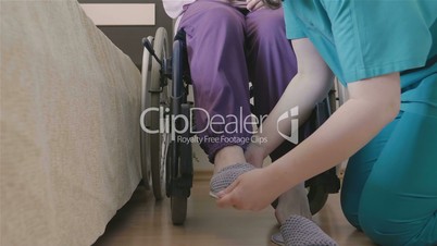 Female caregiver helping senior woman to put her shoes