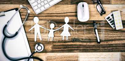 Paper cut out family chain with various medical equipment and keyboard