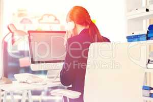 Composite image of businesswoman talking on phone at desk in office