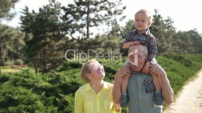 Cute boy sitting on grandfather's shoulder outdoor