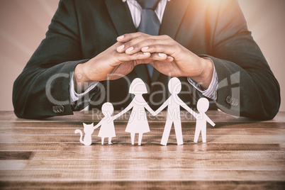 Composite image of underwriter protecting family in paper with his hands