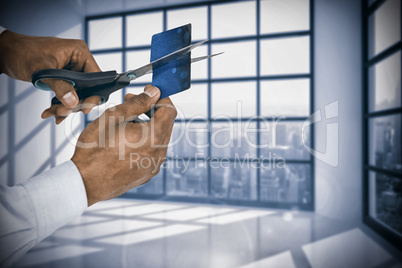 Composite image of businessman cutting credit card with scissors