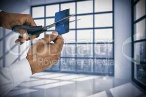 Composite image of businessman cutting credit card with scissors