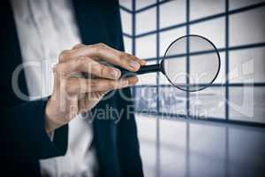 Composite image of mid section of businesswoman holding magnifying glass