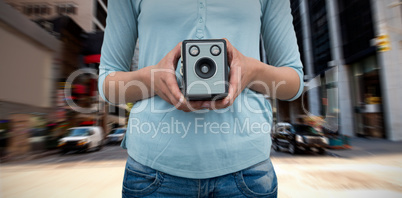 Composite image of mid section of female photographer holding vintage camera