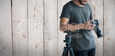 Composite image of happy male photographer looking at digital camera