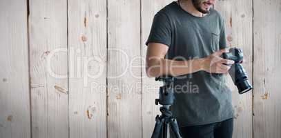 Composite image of happy male photographer looking at digital camera