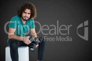 Composite image of portrait of male photographer holding camera while sitting on seat